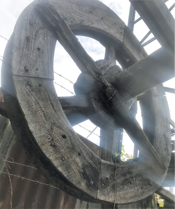 Salvaged wooden six spoke pulley wheel complete with axle/shaft.